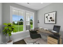 Bright office space with a modern glass desk and large windows overlooking the green landscape at 54 Merle Dr, Wendell, NC 27591