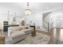 Bright living room featuring a chandelier, an area rug, and hardwood floors at 124 Ferrell W Rd, Apex, NC 27523