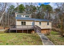 Charming, tan home with a deck, a walkway, and windows under a cloudy blue sky at 14 Winchester Ct, Durham, NC 27707