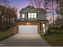 Charming two-story home featuring stone accents, attached two-car garage, and landscaped front yard at 1404 Vanguard Pl, Durham, NC 27713