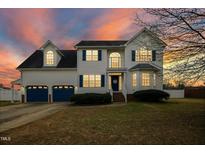 Charming two-story home with blue shutters, a two-car garage, and a beautifully landscaped front yard at dusk at 1421 Harvey Johnson Rd, Raleigh, NC 27603