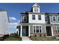 Charming, new construction two-story home with stone accents, a quaint porch, and vibrant blue front door at 1573 Wendell Valley Blvd, Wendell, NC 27591