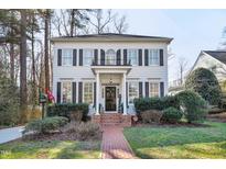 Charming two-story home with black shutters, columns, well-manicured lawn, and brick walkway at 2725 Rosedale Ave, Raleigh, NC 27607