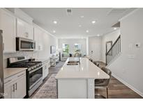 Modern kitchen with stainless steel appliances, a large island, and a view into the bright living room at 679 Mirkwood, Apex, NC 27523