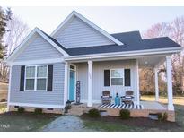 Charming home featuring gray siding, black shutters, and a welcoming front porch with rocking chairs at 103 1St St, Haw River, NC 27258