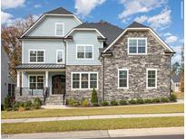 Stunning exterior view of a two-story home with stone accents, manicured lawn, and a welcoming front porch at 123 Stone Park Dr, Wake Forest, NC 27587