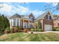 Charming two-story brick home with manicured lawn and attached two car garage at 12409 Village Gate Way, Raleigh, NC 27614