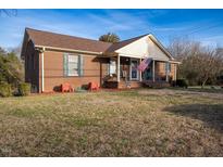 Charming brick home featuring a cozy front porch, landscaped yard, and classic architectural details at 1303 Cherry Dr, Burlington, NC 27215