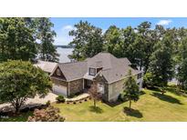 Beautiful stone home featuring a manicured lawn and stunning lake views at 1315 Sagamore Dr, Louisburg, NC 27549