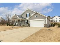 Charming gray home featuring a two-car garage and meticulously maintained lawn at 149 Brickhouse Ln, Fuquay Varina, NC 27526