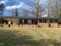 Charming brick home with covered front porch, black shutters, and a well-manicured front lawn at 209 Reade Dr, Roxboro, NC 27573