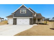 Charming two-story home with a three car garage, stone accents, and a well-manicured lawn on a sunny day at 51 Blackberry Ln, Benson, NC 27504