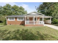 Charming brick home with a welcoming front porch and well-manicured lawn at 709 Fitzgerald Dr, Raleigh, NC 27610