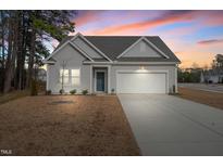 Charming single-Gathering home featuring a two-car garage and a well-manicured front yard at sunset at 88 Molly Mac Ln, Angier, NC 27501