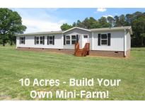 Charming single-story home featuring wood steps, light siding, black shutters, and a well-maintained lawn on a sunny day at 9115 Nc 157, Rougemont, NC 27572
