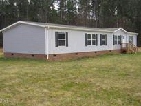 Charming home featuring a mix of gray siding and brick foundation, complemented by black shutters and a natural wooded backdrop at 9115 Nc 157, Rougemont, NC 27572