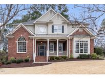 Charming two-story brick home with a covered front porch and manicured landscaping at 100 Tavernelle Pl, Cary, NC 27519