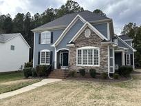 Charming two-story home featuring stone accents, blue siding, and a well-manicured front yard at 1233 Dunn Creek Xing, Wake Forest, NC 27587