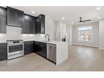 Modern kitchen with black cabinetry, stainless steel appliances, and a center island with a waterfall countertop at 226 Woodsborough Pl, Raleigh, NC 27601