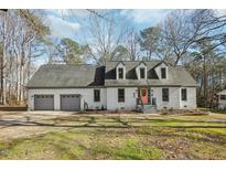 Charming white brick home with gray trim, two-car garage, and inviting peach front door at 2612 Huntsman Trl, Zebulon, NC 27597