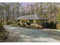 Charming single-story home with gravel driveway nestled amongst mature trees and landscaping at 3514 Ridge Rd, Durham, NC 27705