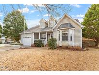 Charming two-story home with well-maintained lawn, attached garage, inviting front porch, and a lovely, landscaped front yard at 408 E Maple Ave, Holly Springs, NC 27540