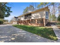 Side angle of a tan home featuring a brick foundation and a spacious driveway, surrounded by mature trees at 6301 King Lawrence Rd, Raleigh, NC 27607
