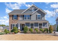 Charming two-story home with a combination of stone and gray siding, a manicured lawn, and trimmed bushes at 710 Legacy Falls S S Dr, Chapel Hill, NC 27517