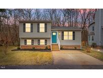 Charming split-level home featuring a quaint front yard, complemented by a vibrant teal-colored front door at 8341 Wynewood Ct, Raleigh, NC 27616