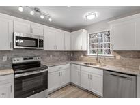 Bright kitchen featuring white cabinets, stainless steel appliances, and modern countertops at 8341 Wynewood Ct, Raleigh, NC 27616