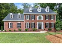 A stately two-story brick home with black shutters and a well-manicured front lawn at 102 Legault Dr, Cary, NC 27513
