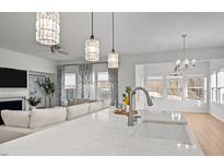 Bright kitchen with modern pendant lighting, stainless steel faucet, white marble counters and an open floor plan to living room at 1026 Janiskee Rd, Durham, NC 27703