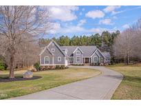 Stunning two-story home with a long driveway and lush front lawn on a sunny day at 108 Springfield Pl, Hillsborough, NC 27278
