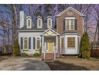Charming two-story home featuring a mix of brick and siding, complemented by a bright yellow front door at 112 Solstice Cir, Cary, NC 27513