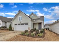 Charming home with light green siding, manicured lawn, and a two-car garage under a partly cloudy sky at 119 Canary Ct, Raleigh, NC 27610