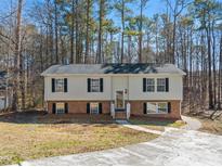 Split-level home featuring light siding, black shutters, brick foundation, and a concrete driveway at 228 Hickory Glen Ln, Durham, NC 27703