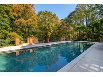 Inviting in-ground pool surrounded by mature trees and decorative brickwork, perfect for relaxation at 303 Laurel Hill Road, Chapel Hill, NC 27514