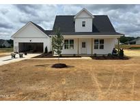 Charming white two-story home with a front-facing garage and freshly landscaped yard and mulched flowerbeds at 432 Springtooth Dr, Zebulon, NC 27597