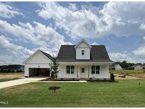 Charming exterior view of a white home with a manicured lawn and a detached garage at 432 Springtooth Dr, Zebulon, NC 27597