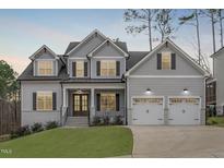Charming two-story home featuring a manicured lawn, gray siding, dormer windows and a two car garage at 4508 Chandler Creek Pl, Apex, NC 27539