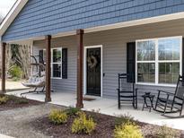 Inviting covered front porch featuring rocking chairs and swing, enhancing the home's curb appeal at 5 Morning Dove Ct, Clayton, NC 27520