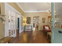 Bright living room featuring hardwood floors, white trim, a chandelier, and glass french doors at 613 S Fuquay Ave, Fuquay Varina, NC 27526
