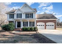 Charming two-story home with white siding, black shutters, and a brick two car garage on a sunny day at 84 Sycamore Lake Rd, Siler City, NC 27344