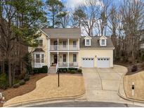 Charming yellow two-story home with a double front porch, well-manicured lawn, and a two-car garage at 108 Shady Creek Trl, Cary, NC 27513