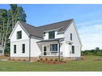Beautiful modern farmhouse with white siding, black trim, and manicured lawn at 1467 Antioch Church Rd, Timberlake, NC 27583