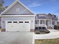 Charming home featuring gray siding, a two-car garage, and a welcoming front porch at 182 Inverness St, Zebulon, NC 27597