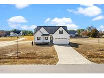 Charming two-story home featuring a long driveway, attached two-car garage, and landscaped yard at 20 Wildflower Ln, Franklinton, NC 27525