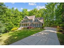 Beautiful two-story home with lush landscaping, a welcoming porch, and a long driveway surrounded by trees at 260 Culbreth Rd, Chapel Hill, NC 27516