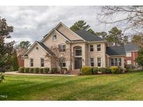 Elegant brick home boasts a well-manicured lawn, mature trees, and a welcoming entrance at 325 Hogans Valley Way, Cary, NC 27513