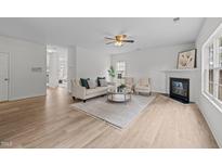 Bright living room features a fireplace, ceiling fan, and wood flooring, providing a warm and inviting atmosphere at 4207 Hampstead Village Dr, Durham, NC 27703
